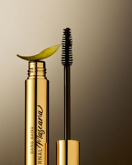 The Eternal mascara and its brush, a petal resting on the tube
