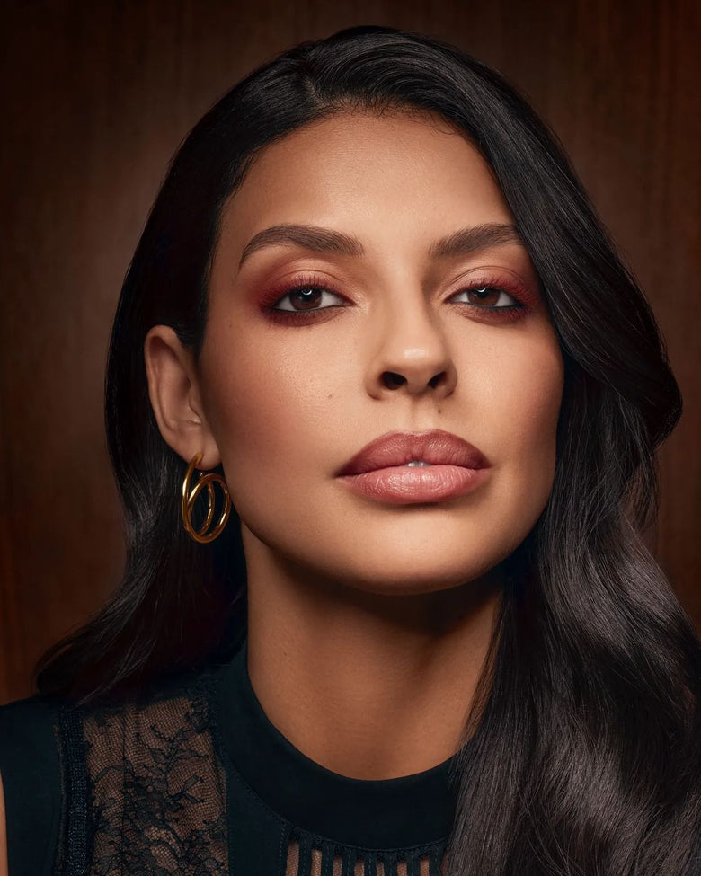Portrait of a woman facing the camera, burgundy eyeshadow and nude lips
